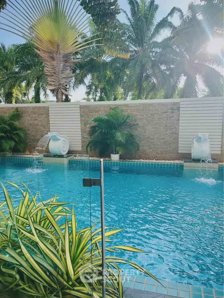 Luxurious pool area with cascading water features and lush palm trees.