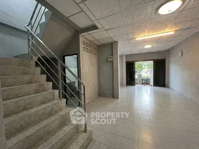Spacious interior with tiled flooring and modern staircase, ideal for versatile living or office space.
