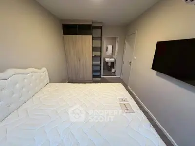 Modern bedroom with stylish wardrobe and wall-mounted TV, featuring a glimpse of an ensuite bathroom.