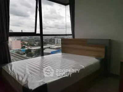 Spacious bedroom with large windows offering a stunning city view, perfect for urban living.