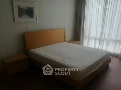 Spacious bedroom with large window and modern wooden furniture.