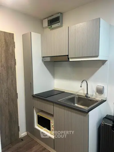 Compact modern kitchen with sleek cabinetry and built-in appliances in a cozy apartment.