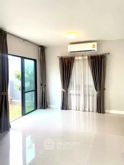 Spacious living room with large windows and elegant curtains, featuring a modern air conditioning unit.