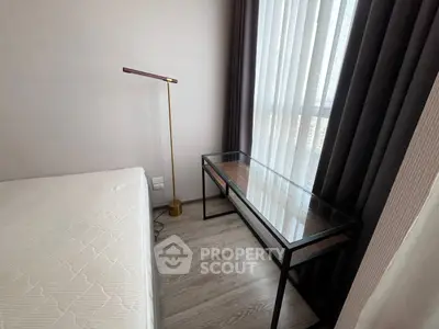Modern bedroom corner with sleek glass desk and elegant floor lamp near large window.