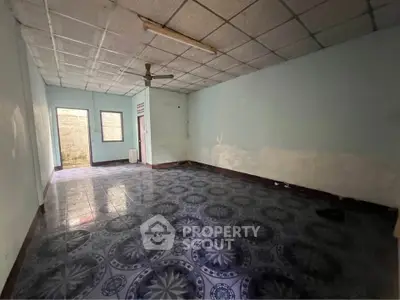 Spacious empty room with patterned tile flooring and ceiling fan, ideal for customization.