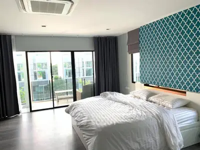 Spacious modern bedroom with large windows and balcony access, featuring stylish decor and ample natural light.