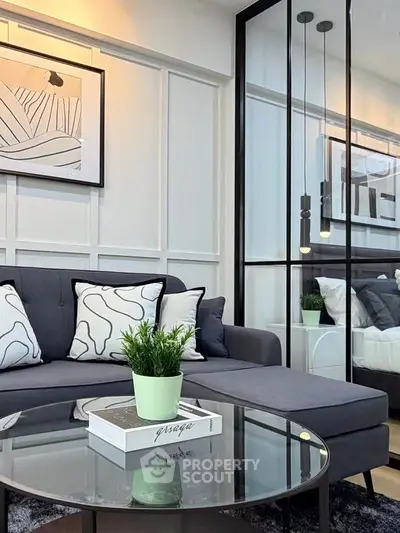 Modern living room with stylish decor and glass partition leading to bedroom.