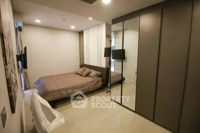 Modern bedroom with sleek design and mirrored wardrobe in a stylish apartment.