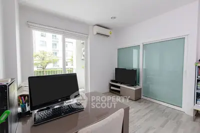 Modern study room with sleek desk, computer setup, and balcony view in a bright apartment.