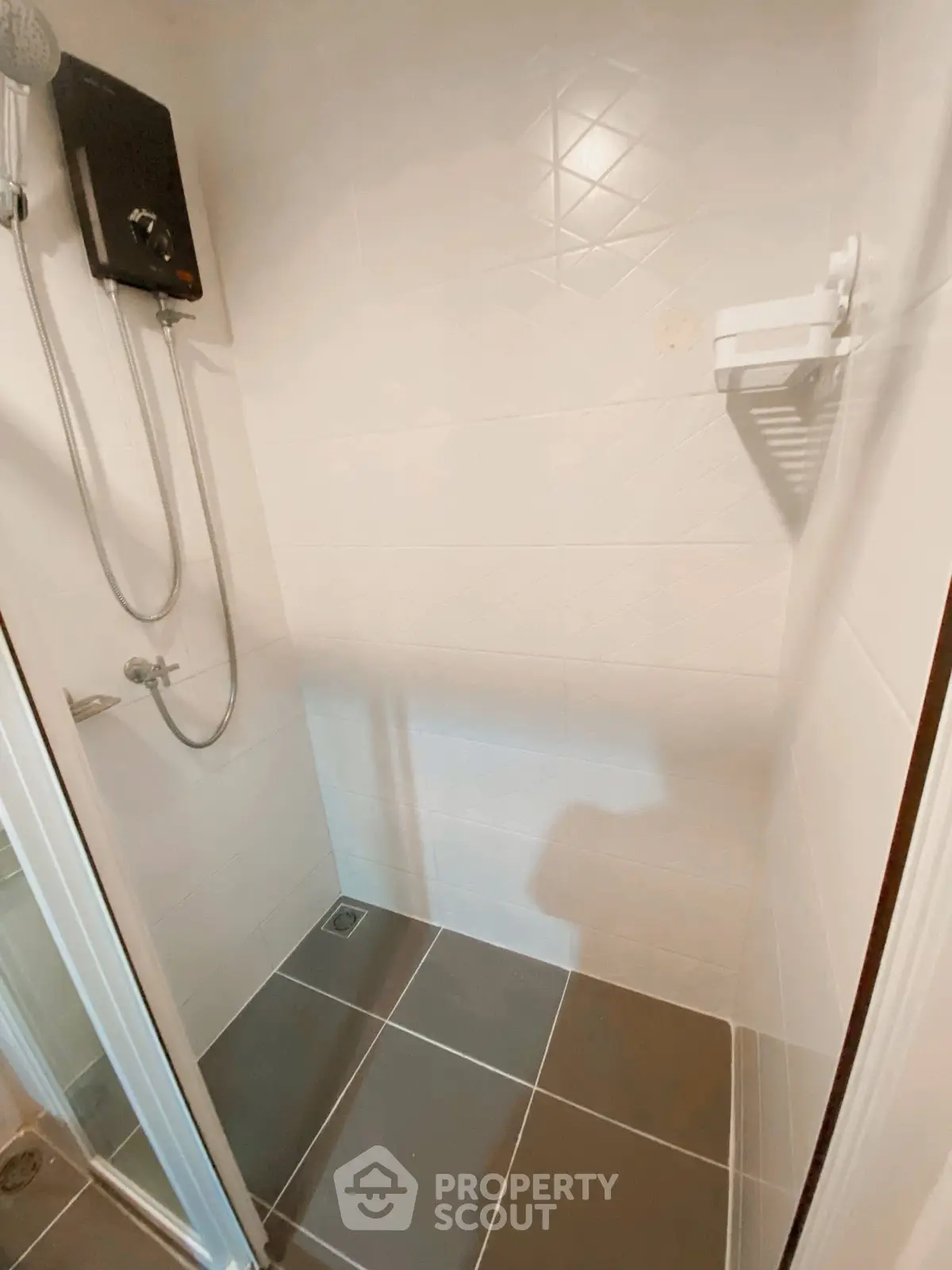 Modern shower area with sleek tiles and showerhead in a compact bathroom.