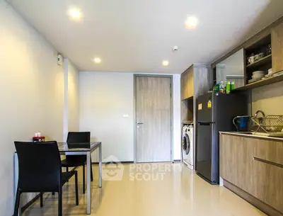 Modern kitchen with dining area, washing machine, and sleek cabinetry in a stylish apartment.
