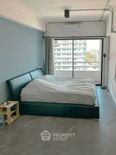 Spacious bedroom with modern decor and large window offering city views.