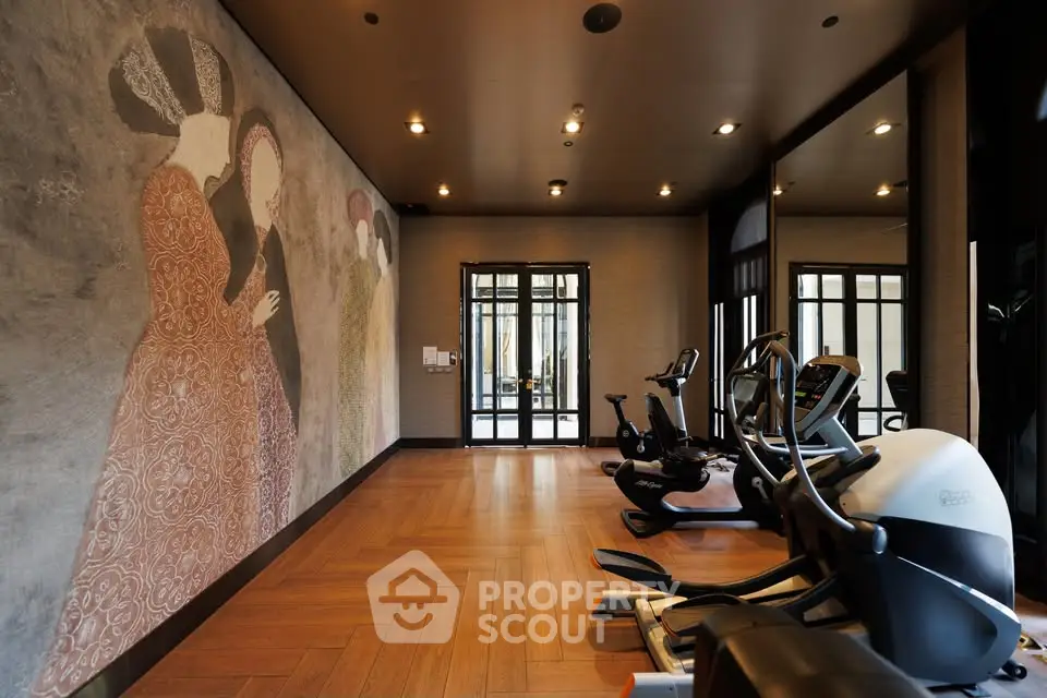 Luxurious gym with modern equipment and artistic wall mural in upscale property.