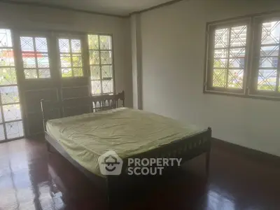 Spacious bedroom with polished hardwood floors and ample natural light streaming through large stained-glass windows, perfect for a serene retreat.