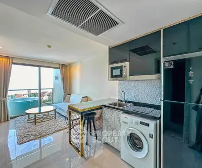 Modern open-plan living room with kitchen, featuring a washing machine and balcony with a view.