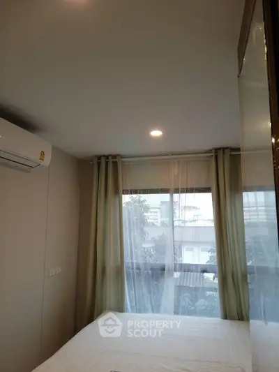 Cozy bedroom with large window and air conditioning, offering a serene view of the cityscape.
