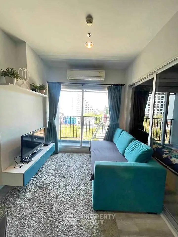 Modern living room with balcony view, featuring sleek furniture and abundant natural light.