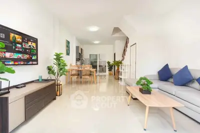 Spacious modern living room with open kitchen, stylish decor, and natural light.