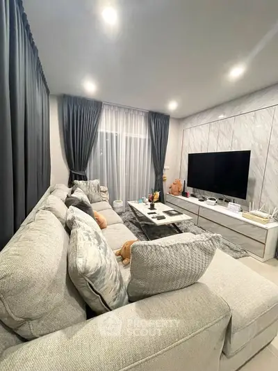 Luxurious living room with plush sofa and large TV, perfect for relaxation and entertainment.