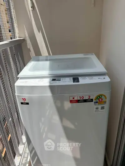 Modern washing machine on a balcony with sunlight streaming in, perfect for urban living convenience.