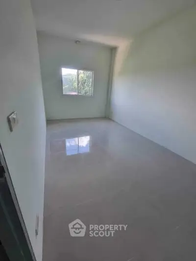 Spacious empty room with large window and glossy tiled floor