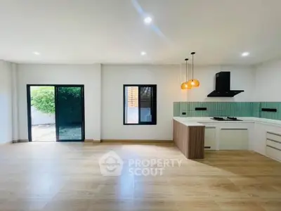 Spacious modern kitchen with open layout and stylish lighting, featuring large windows and wooden flooring.