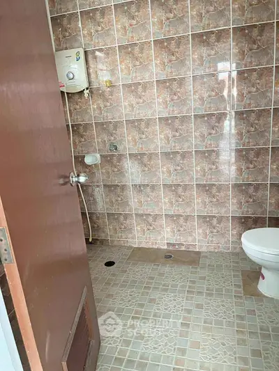 Compact bathroom with tiled walls and floor, featuring a water heater and toilet.