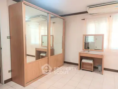 Spacious bedroom with mirrored wardrobe and vanity set, perfect for modern living.