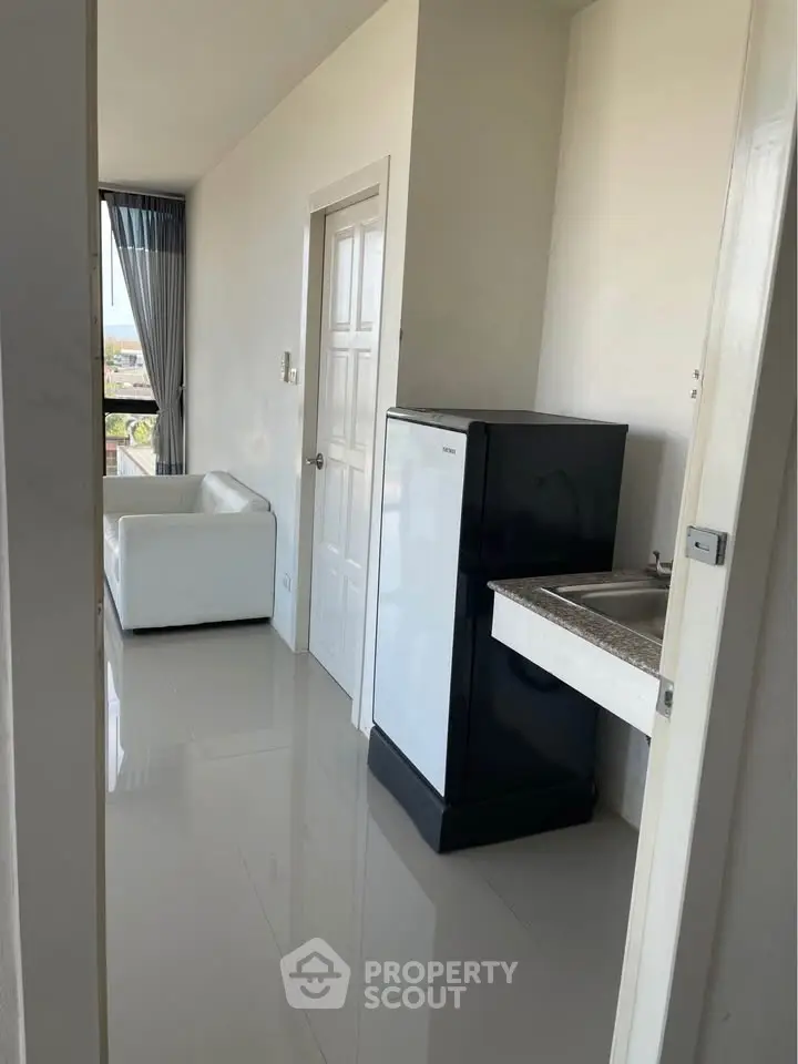 Modern apartment hallway with sleek fridge and cozy seating area