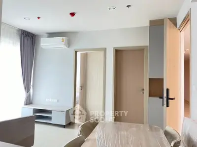 Modern apartment interior with dining area and air conditioning, featuring neutral tones and natural light.