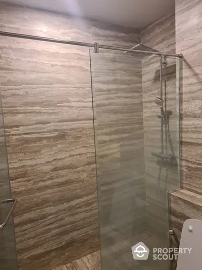 Luxurious bathroom with modern glass shower enclosure and elegant stone tiles.