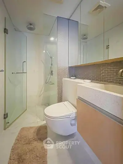 Modern bathroom with glass shower and wall-mounted toilet in luxury apartment.