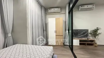 Modern bedroom with mirrored wardrobe and air conditioning, featuring stylish decor and ample natural light.