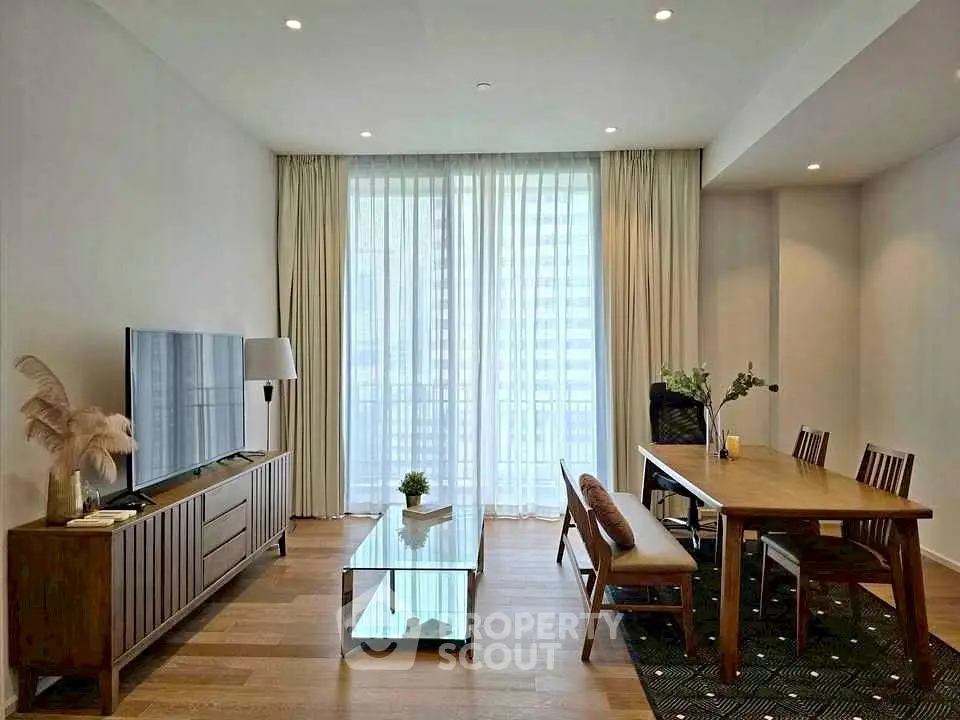 Modern living room with elegant dining area and large TV, featuring floor-to-ceiling windows and stylish decor.