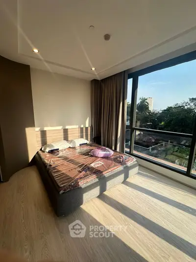 Spacious bedroom with large windows and scenic view, featuring modern decor and natural light.