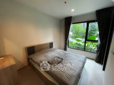 Modern bedroom with large window and garden view in a stylish apartment.