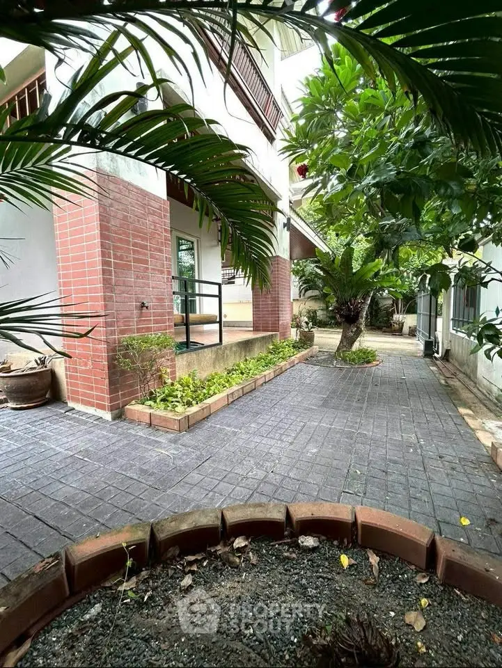 Charming garden entrance with lush greenery and brick accents in a serene residential setting.