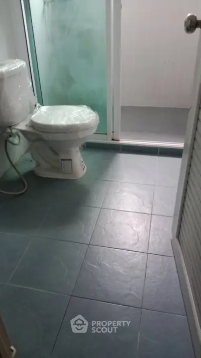 Modern bathroom with tiled floor and glass shower enclosure, featuring a sleek toilet design.