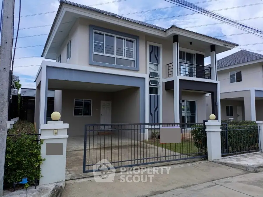 Modern two-story house with gated driveway and balcony in suburban neighborhood.