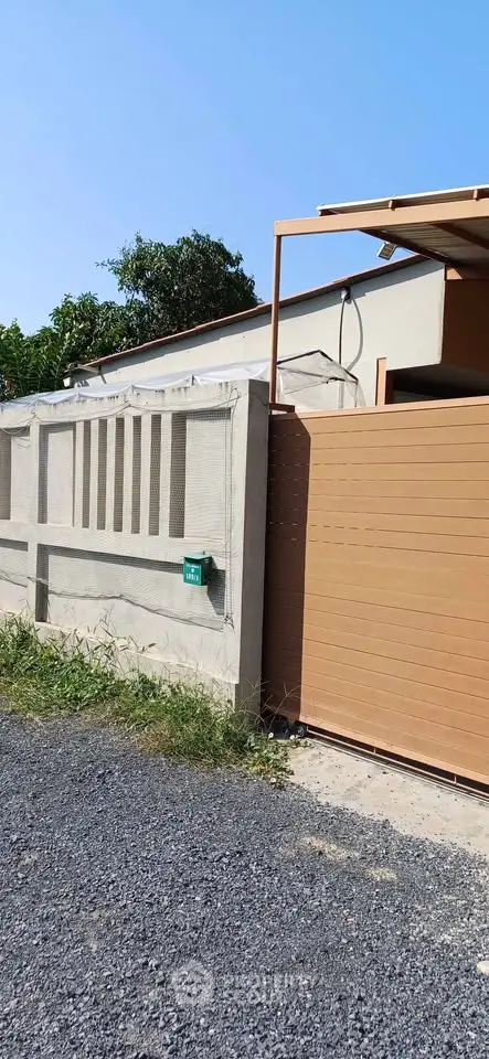 Modern exterior view of a residential property with a stylish wooden gate and concrete wall.