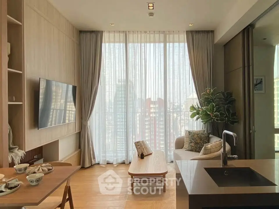 Modern living room with open kitchen, large windows, and city view, featuring stylish decor and natural light.
