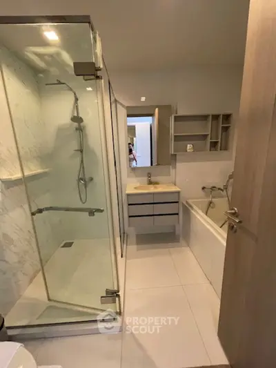 Modern bathroom with glass shower and bathtub in sleek apartment
