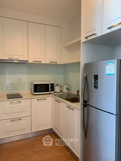 Modern kitchen with sleek white cabinets and stainless steel appliances.