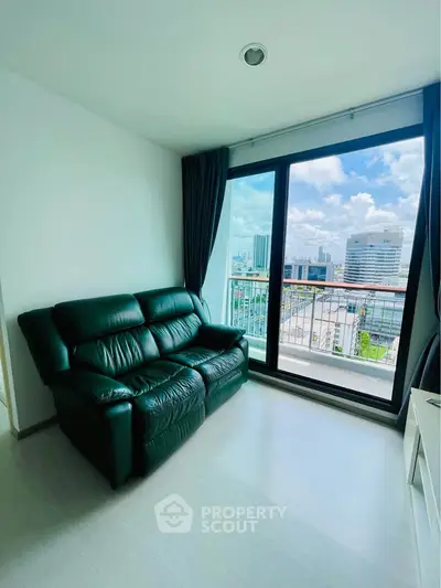 Modern living room with large window and city view, featuring a sleek black leather sofa.