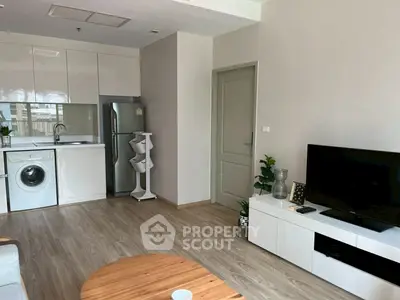 Modern open-plan living room with kitchen, featuring sleek appliances and stylish decor.