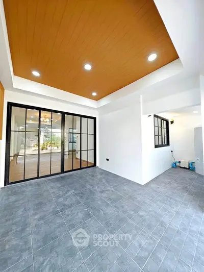 Spacious modern living area with sliding glass doors and stylish ceiling design.