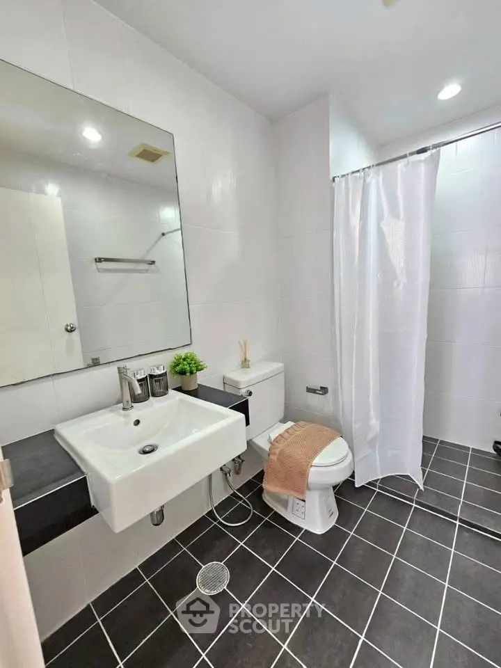 Modern bathroom with sleek fixtures and stylish tile flooring, featuring a spacious shower area and elegant sink.