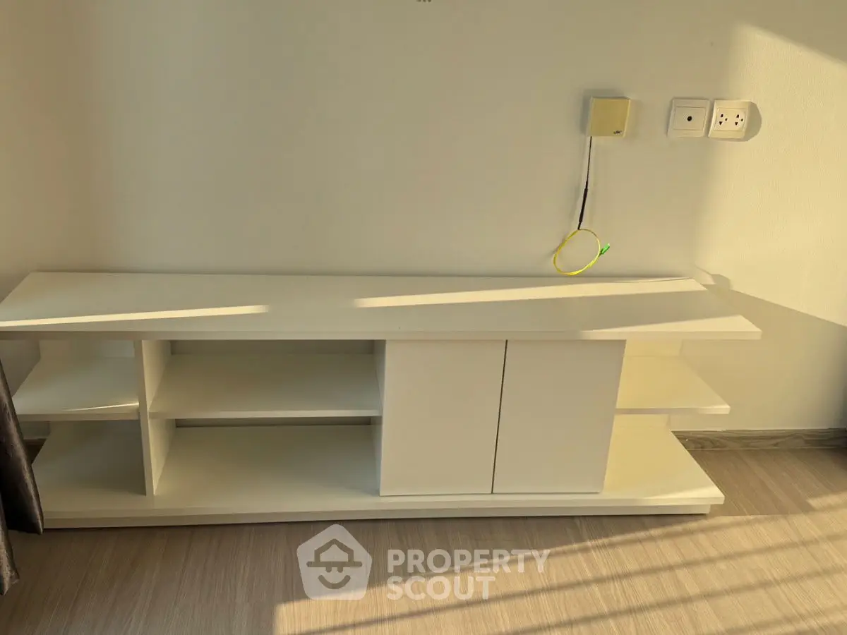 Modern minimalist white TV stand with sunlight streaming in, perfect for sleek living room decor.