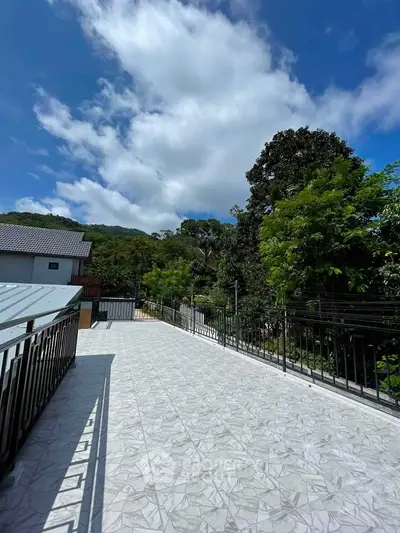 Spacious balcony with scenic views of lush greenery and clear blue skies, perfect for relaxation and outdoor activities.