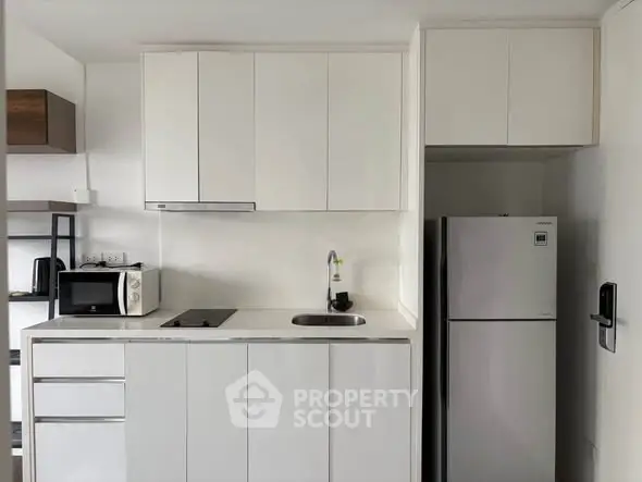 Modern compact kitchen with sleek white cabinets and built-in appliances, perfect for urban living.